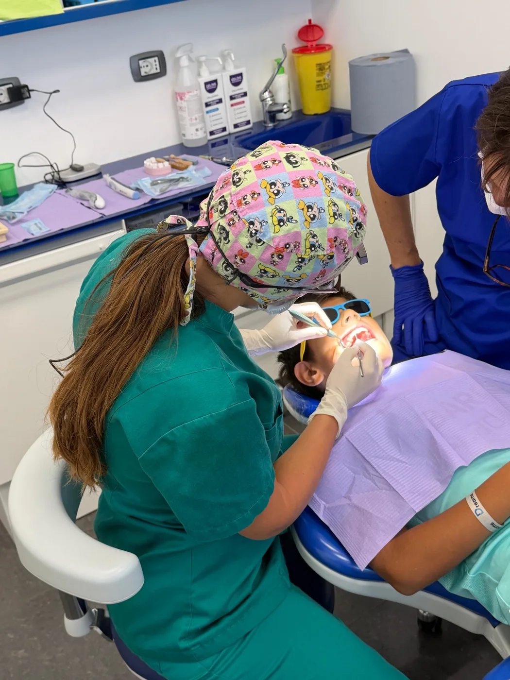 La Dott.ssa Giorgia controlla con calma i denti di un bambino sereno, con l'assistente accanto